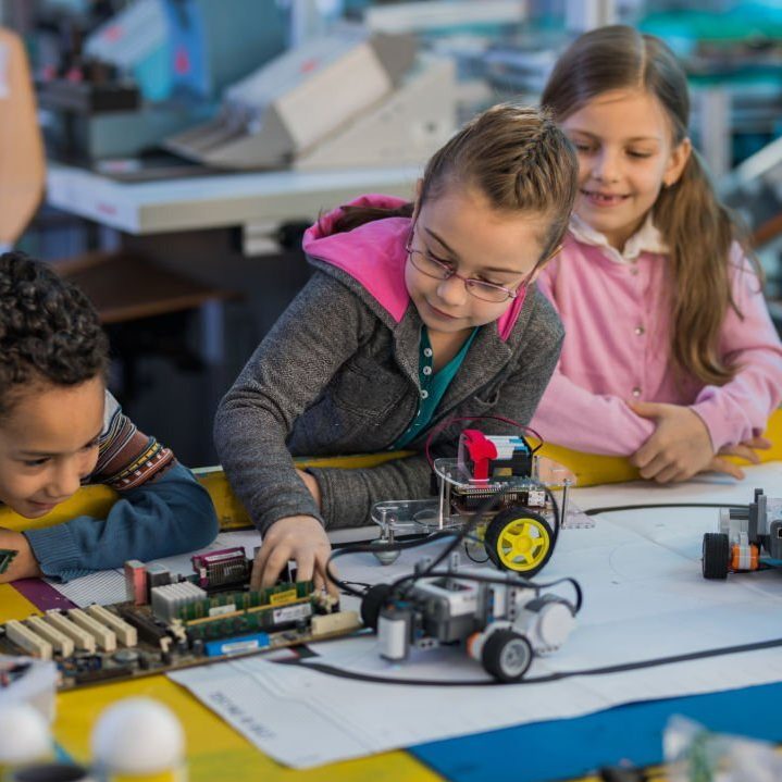 Group of small kids working on motherboard and robots in laboratory.